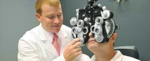 Optometrist performing comprehensive eye exam on mature patient.